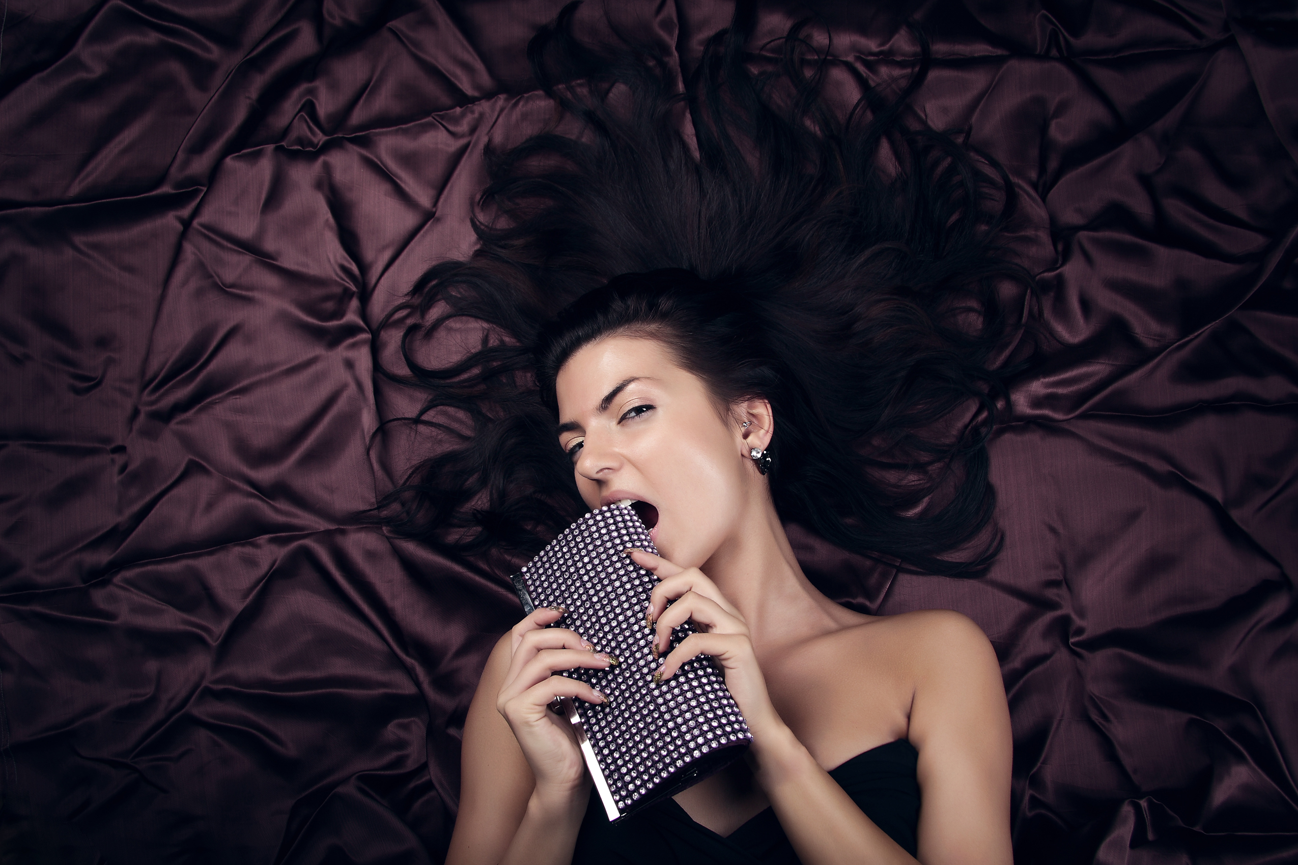 Glamour lady with expensive fashion ladies' handbag laying on brown background. Close-up face photo with copyspace.