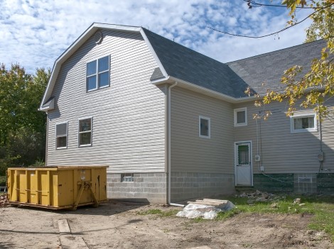 Home construction with gabled roof design and trash receptacle