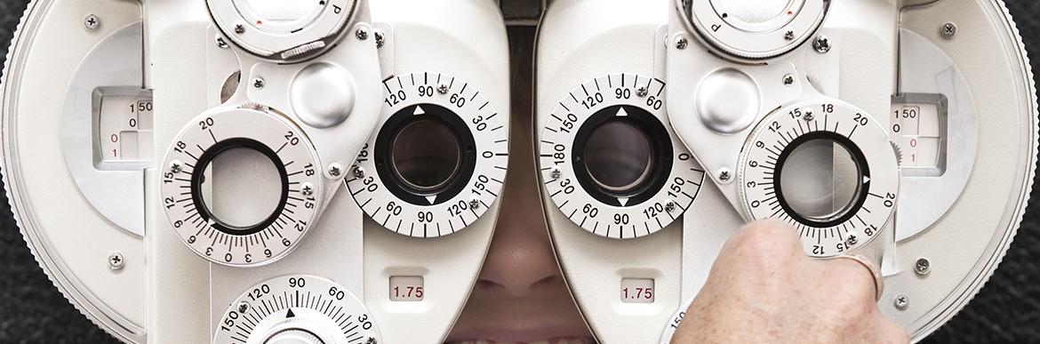 An optometrist adjusts the dials on the phoropter during an eye test