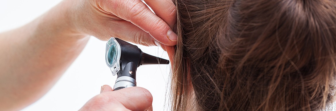 Ear examining with an otoscope, isolated background