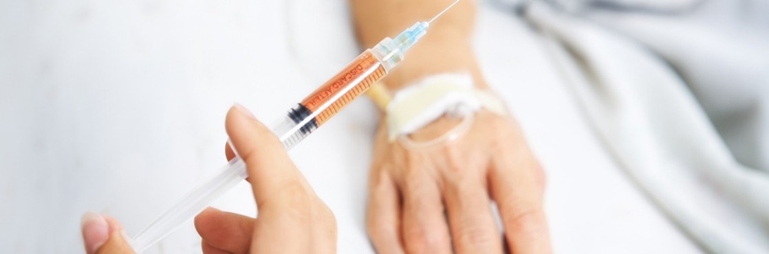 Hand holding injection with patient hand on background
