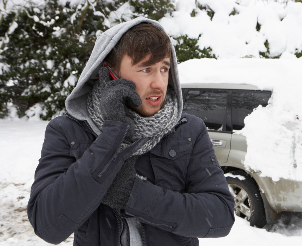 Young man in snow with broken down car
