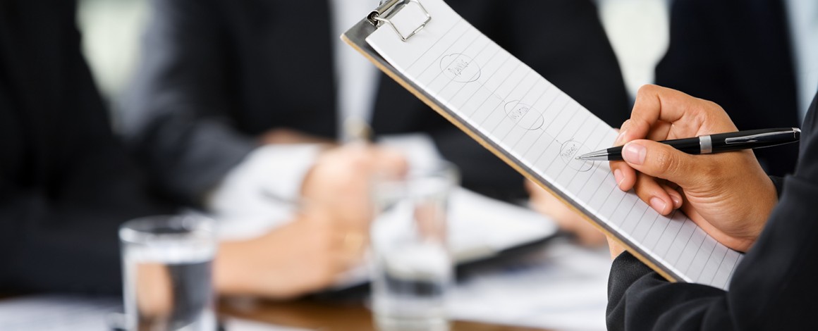 Hand writing with other business people in background