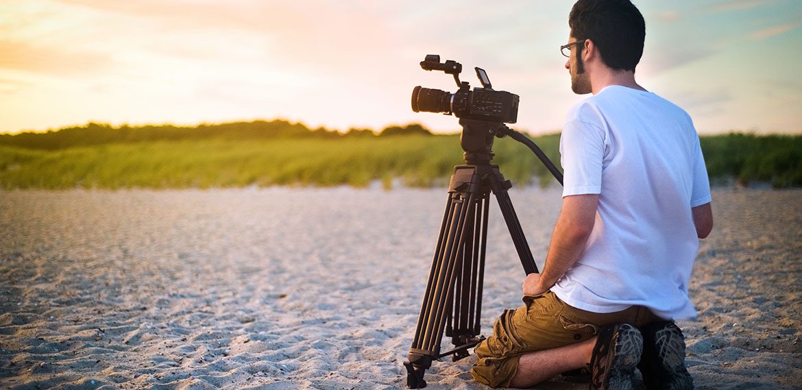 A videographer documenting a sunset on the beach.