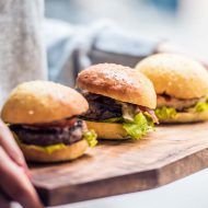 Three delicious hamburgers on wooden board. Toned image