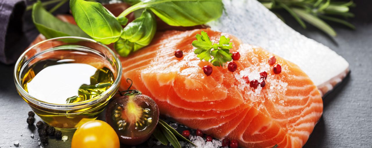 Delicious portion of fresh salmon fillet with aromatic herbs, spices and vegetables - healthy food, diet or cooking concept