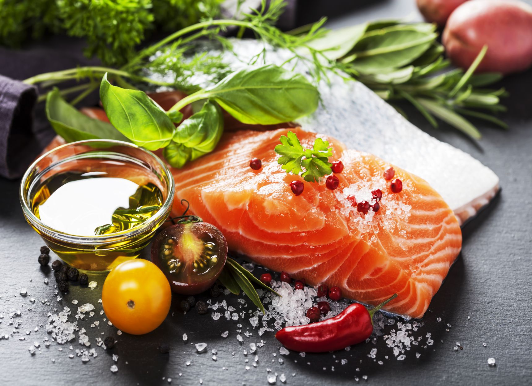 Delicious portion of fresh salmon fillet with aromatic herbs, spices and vegetables - healthy food, diet or cooking concept