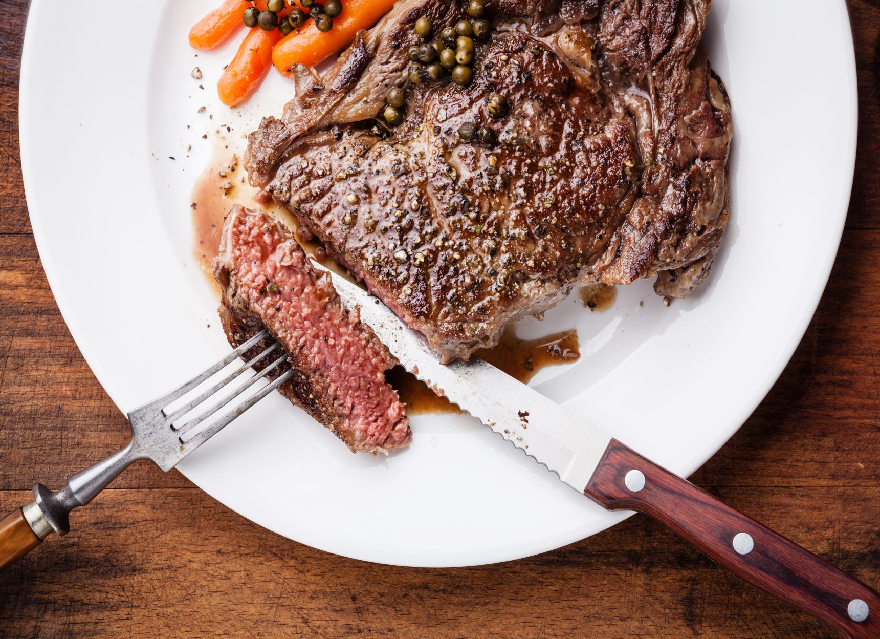 Medium rare grilled Beef steak on fork with green pepper on white plate