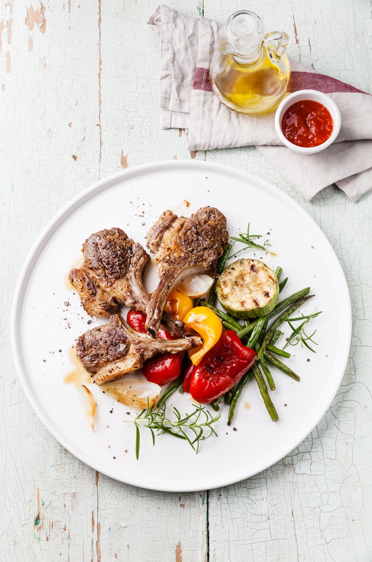 Roasted lamb ribs with spices and grilled vegetables on blue textural background