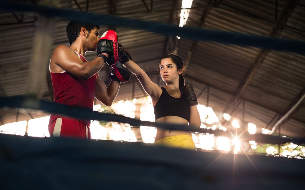Young woman exercising with trainer at boxe and self defense lesson. Copy space
